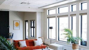 A modern living room with a sofa, ottoman, and a large window providing natural light.