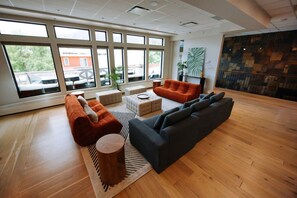 A spacious living area with large windows, a sectional sofa, ottomans, and a coffee table. - Sevenfold | Sleeps 20 | Luxe 7BR Retreat + Hot Tub (Canmore)