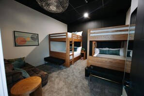 Ein Zimmer mit Etagenbetten, einer Schlafcouch, einem kleinen Tisch und einem Wandbild.