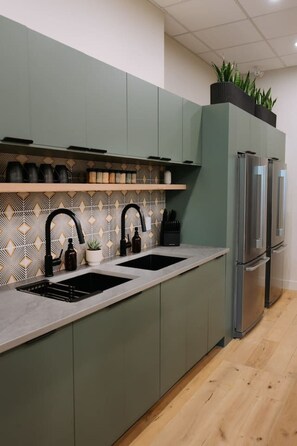 Eine moderne Küche mit zwei Spülen, einer Spritzschutzwand mit geometrischem Muster und einem integrierten Kühlschrank.