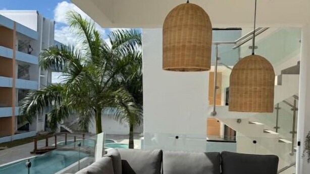 Un salon moderne avec un canapé d’angle, une table basse en bois et une vue sur la piscine.