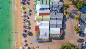 An aerial view of a beachside property with multiple rooms, a row of colorful umbrellas, and a row of parked cars. - El Paraiso apartment (Dominicus)