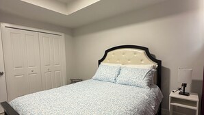 A bedroom with a bed, a nightstand, a wardrobe, and a ceiling light. - 
Cozy guest suite, walking trails (Calgary)