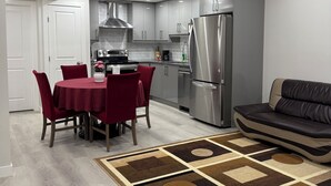 A modern kitchen with grey cabinets, stainless steel appliances, and a dining area with a red table and chairs.