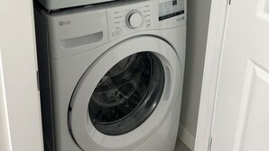 Two stacked white washing machines with control panels and a door.