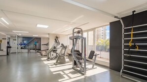 A gym with exercise equipment, a large window, and a view of buildings. - BLI - Complete Condominium With gym and Pool in Goiania (Goiânia)