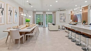 Eine moderne Küche mit Essbereich, Barhocker und einem großen Fenster.