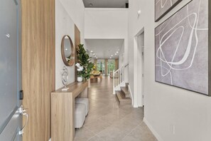 A modern hallway with a wooden reception desk, a mirror, and a large abstract painting.