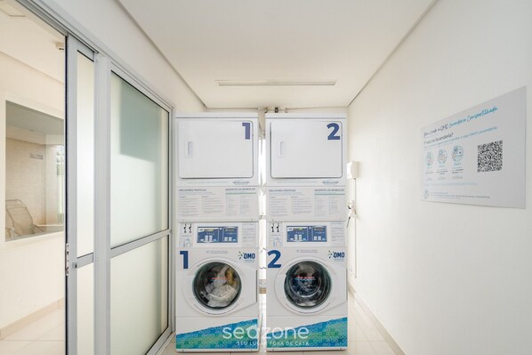A laundry facility with two washing machines, each labeled with numbers 1 and 2. - Studio w/ Pool & gym in Condo - Lhg1603 (Goiânia)