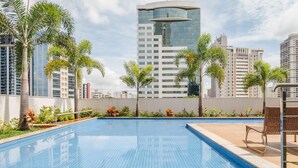 Piscina con piso azul de baldosas, rodeada de palmeras y plantas.