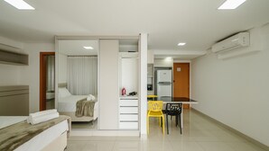 Una habitación de hotel con cama, escritorio, silla y kitchenette.