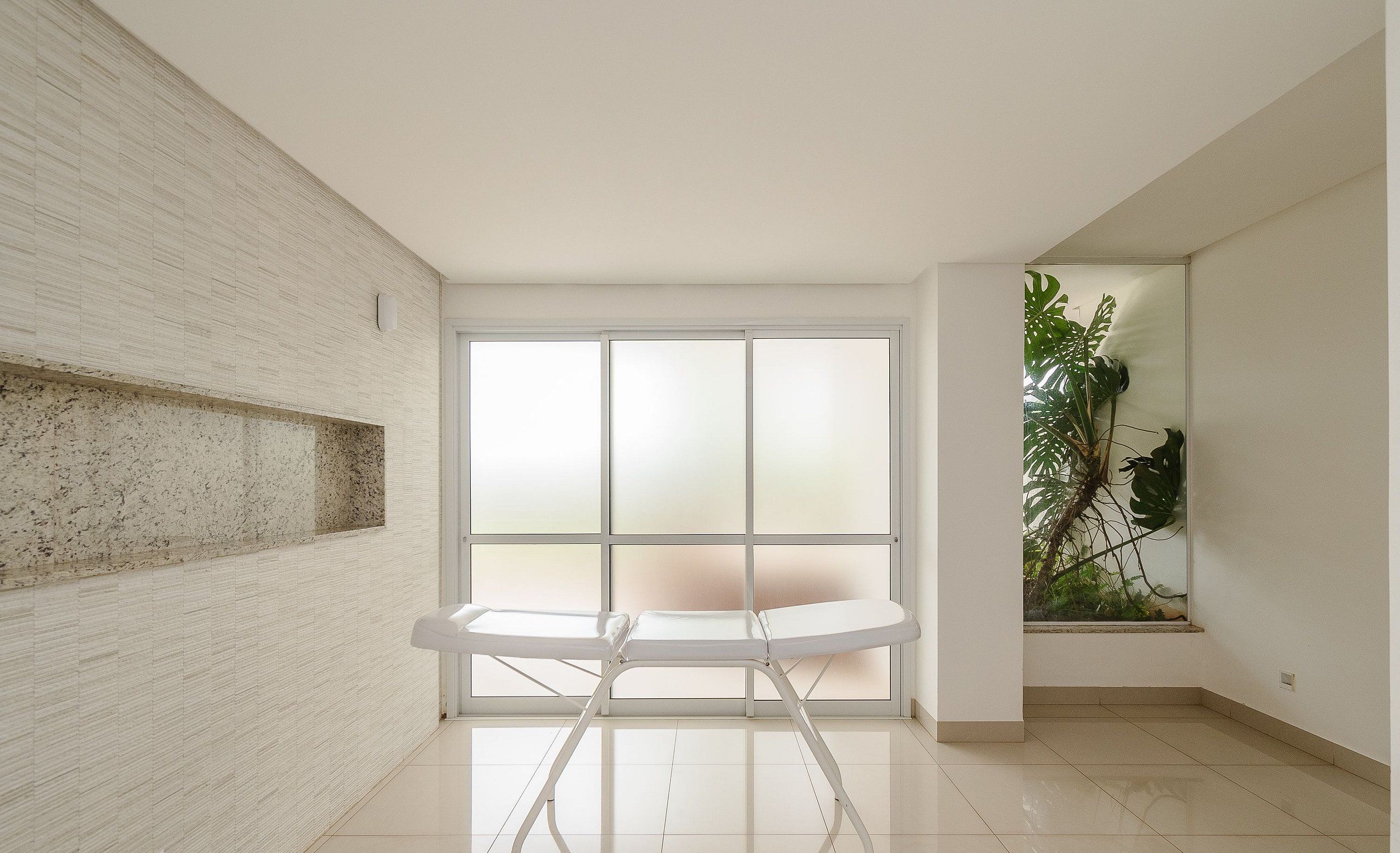 A modern room with a large window, a white bench, and a plant.