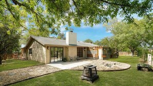A single-story house with a stone facade, large windows, and a patio area. - 10Mins to airport (San Antonio)