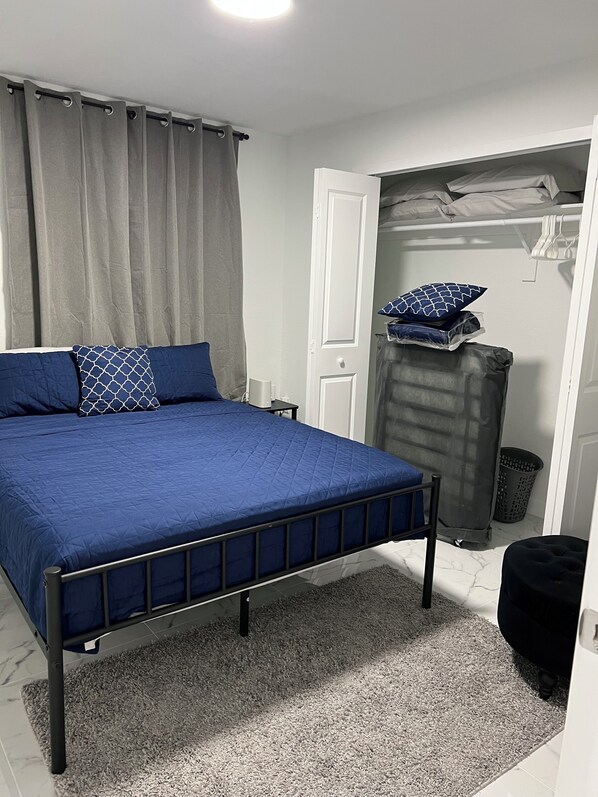 A bedroom with a bed, a wardrobe, and a small trash bin.