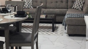 Un salon comprenant un canapé, une table basse et un coin repas avec des chaises et une table dressée pour deux personnes.