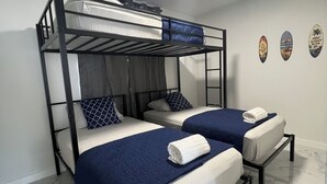 Une chambre avec un lit superposé, deux lits, un luminaire au plafond et trois éléments de décoration murale.