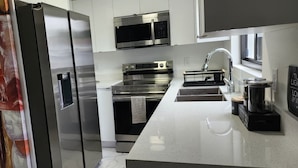 A modern kitchen with stainless steel appliances, a marble countertop, and a view of the city.