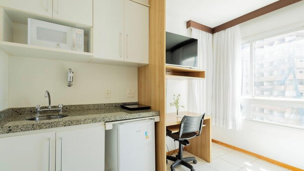 A modern kitchen with white cabinets, a built-in microwave, and a granite countertop. - Modern Flat for Business Asa Norte - Bhy0614 (Brasília)