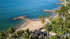 A beach with palm trees, a rocky breakwater, and a clear blue sea. - The Westin Playa Vallarta, An All-Inclusive Resort (Puerto Vallarta)