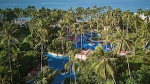 Un resort con un amplio área de piscina rodeada de palmeras y vistas al océano.