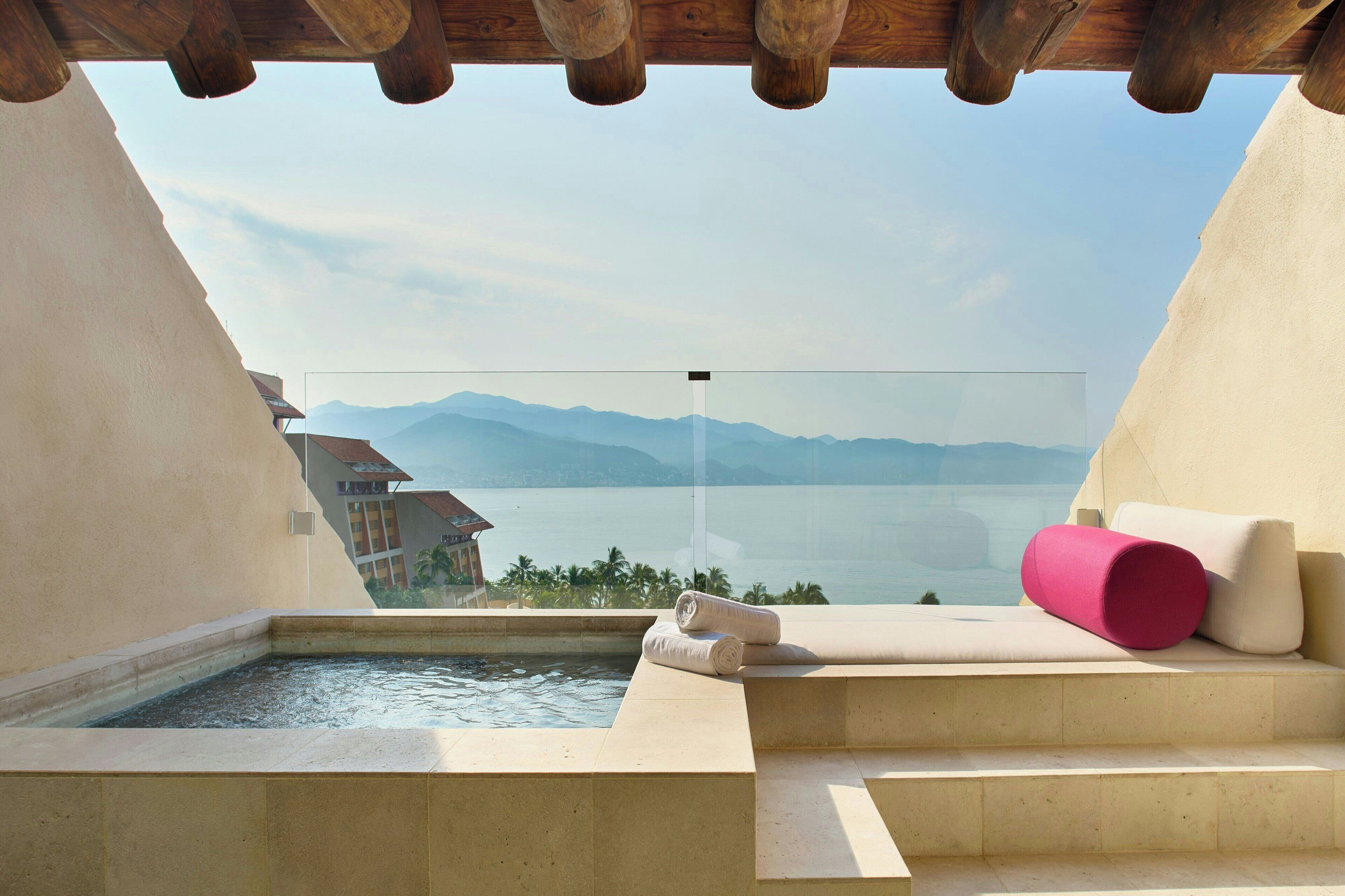 A spa area with a hot tub, a glass-enclosed window, and a view of a lake and mountains.