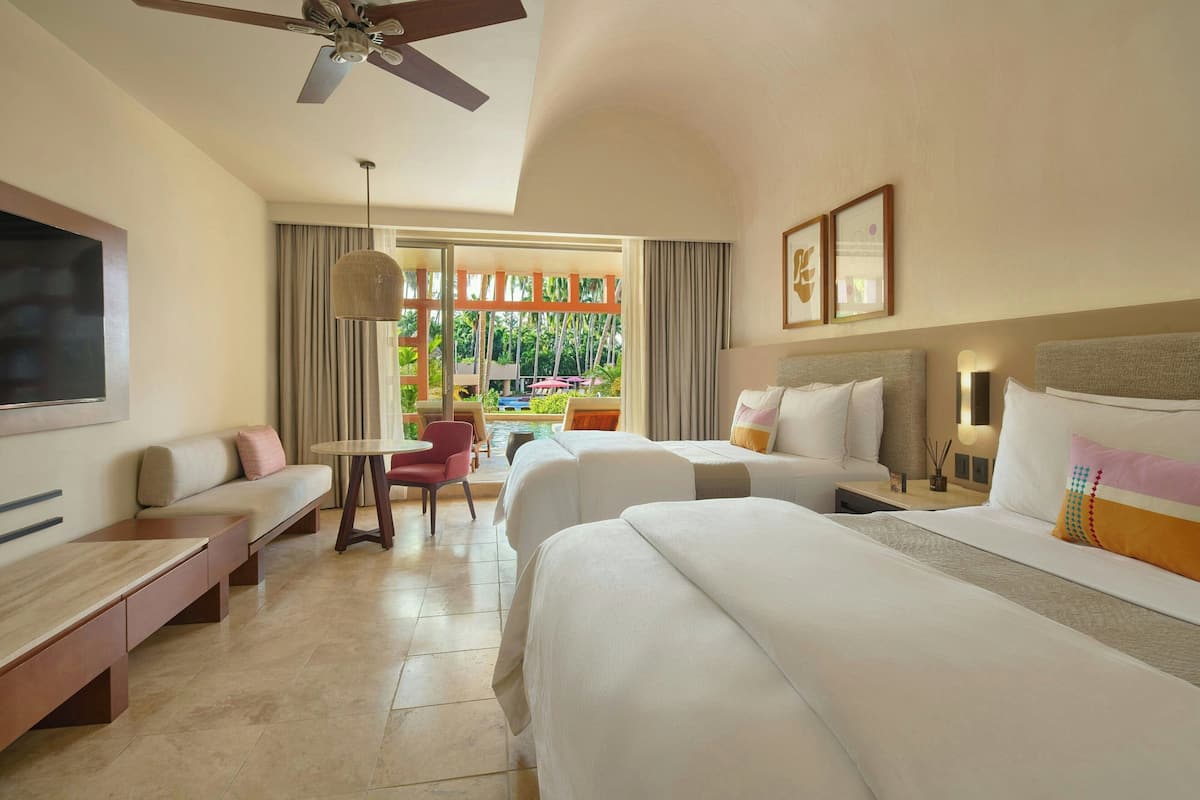 A hotel room with a bed, a sofa, a desk, and a view of the outdoors.