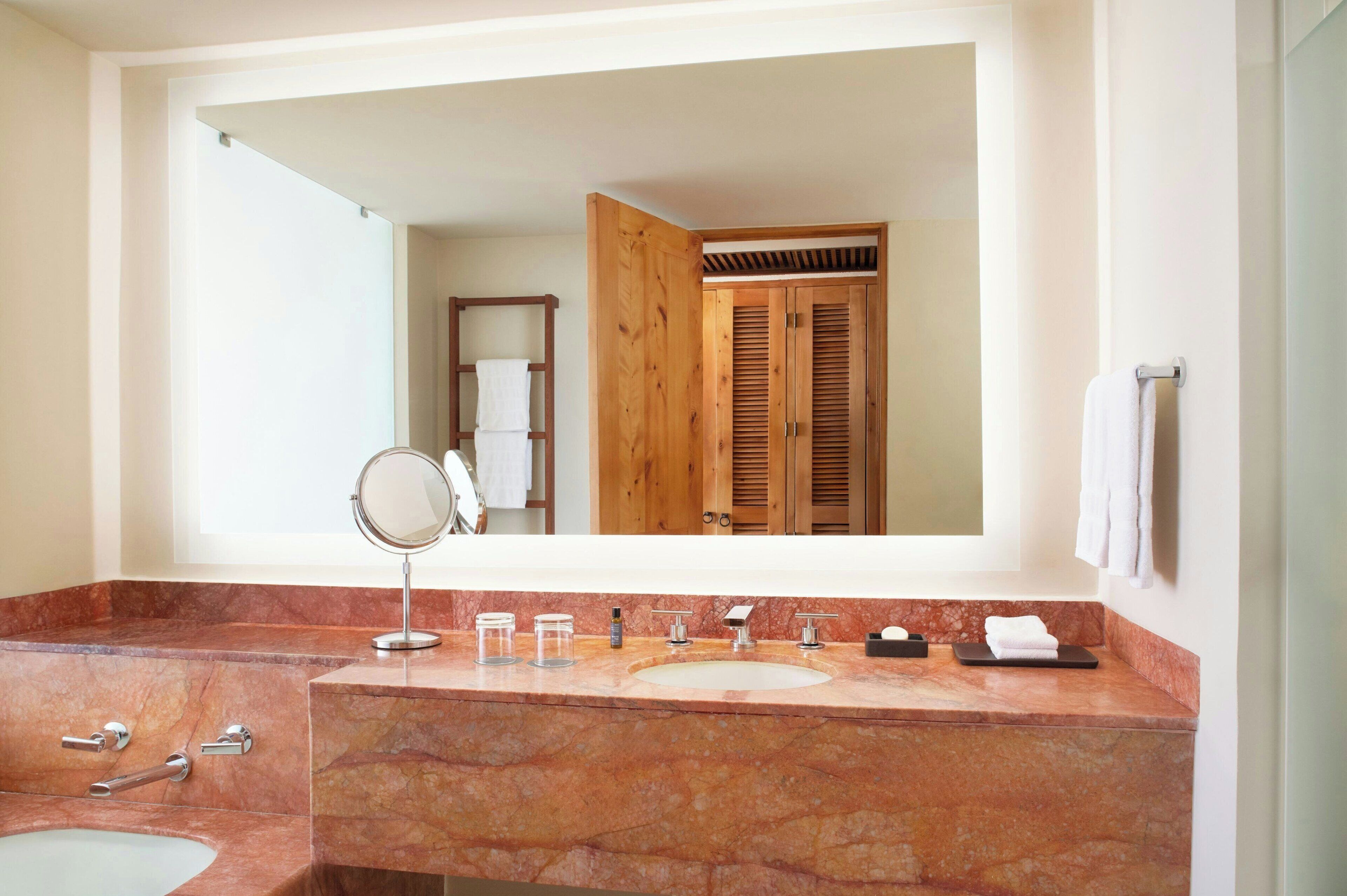 Une salle de bain avec un lavabo en marbre, un miroir et une porte en bois.