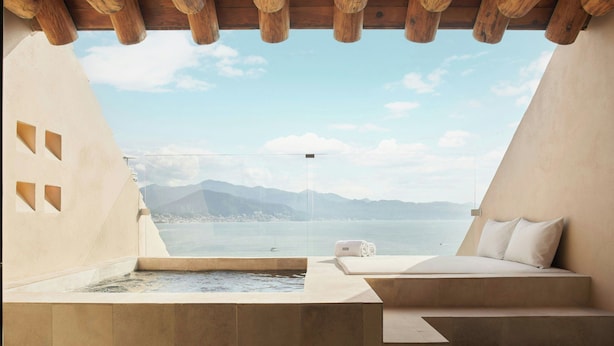 A modern room with a large window overlooking a body of water and mountains. - The Westin Playa Vallarta, An All-Inclusive Resort (Puerto Vallarta)