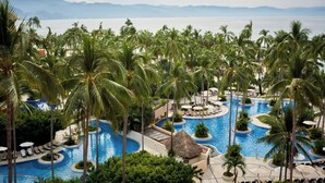 A resort with a large pool surrounded by palm trees and lounge chairs, with mountains in the background. - The Westin Playa Vallarta, An All-Inclusive Resort (Puerto Vallarta)