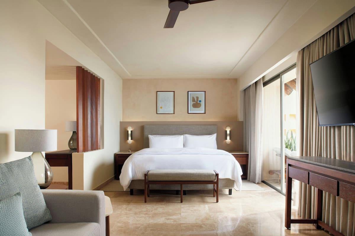 A hotel room with a large bed, a flat-screen TV, a desk, and a chair.