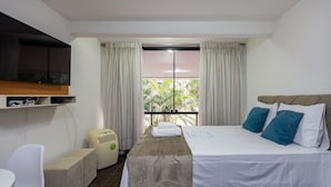 A hotel room with a bed, a TV mounted on the wall, a small table, and a window with curtains. - Beautiful Well-located Studio, Asa Norte Cbd112 (Brasília)