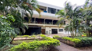 A modern building with a flat roof and multiple balconies, surrounded by lush greenery and palm trees. - Beautiful Well-located Studio, Asa Norte Cbd112 (Brasília)