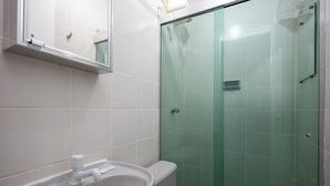 A bathroom with a white sink, a toilet, and a glass-enclosed shower. - Beautiful Well-located Studio, Asa Norte Cbd112 (Brasília)