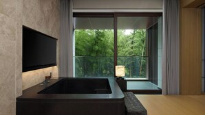 A modern bathroom with a large bathtub, a flat-screen TV, and a view of a balcony with greenery. -  长兴开元名都臻品之选度假酒店 (Huzhou)