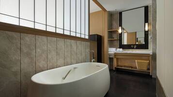 A modern bathroom with a freestanding bathtub, wooden paneling, and a large mirror above the sink.