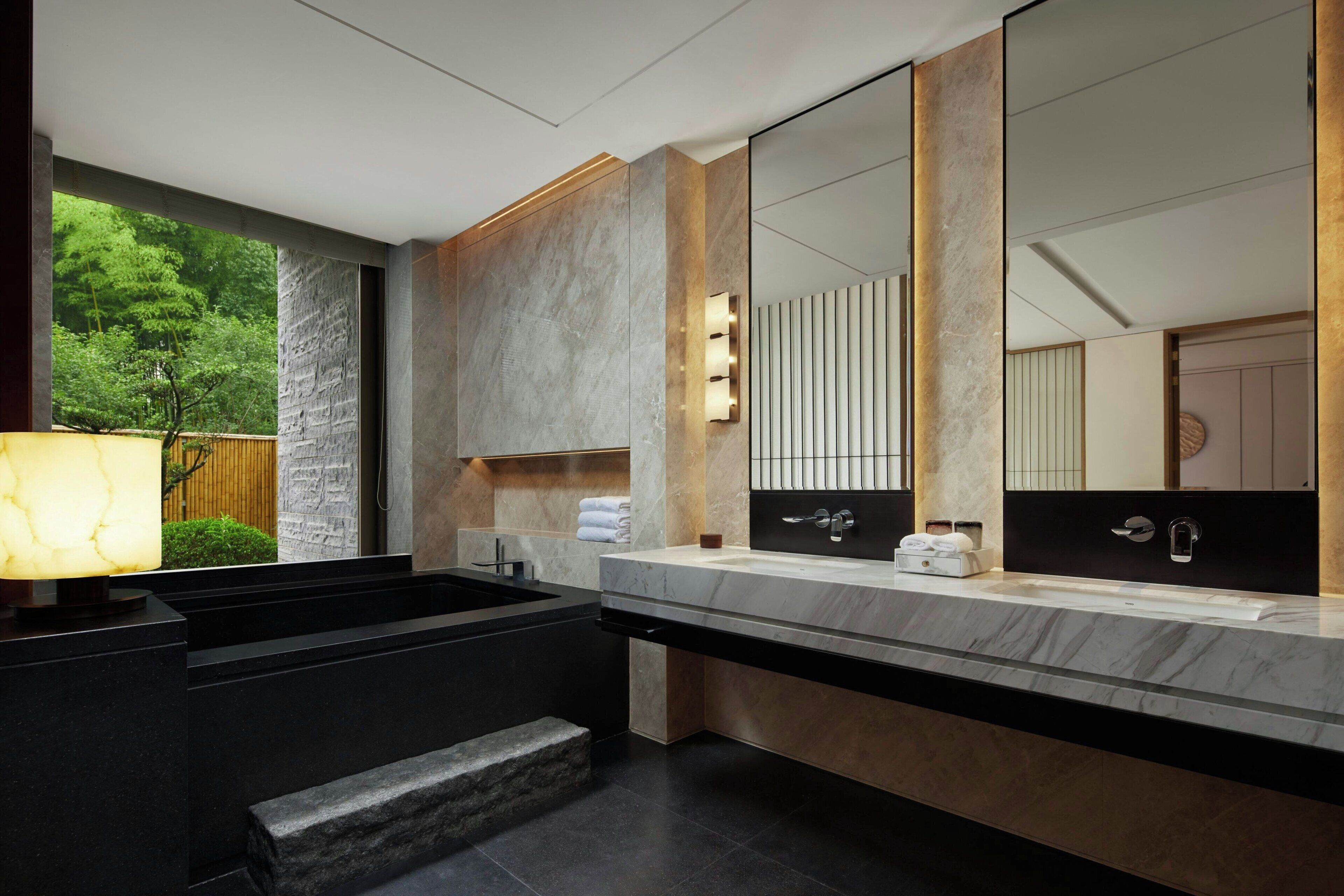 Un baño moderno con un espejo grande, lavamanos dobles y un banco incorporado.