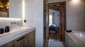 Un baño moderno con tocador de madera, un espejo grande y una bañera.