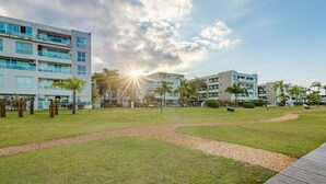 A modern hotel complex with multiple buildings, a well-maintained lawn, and a wooden boardwalk.