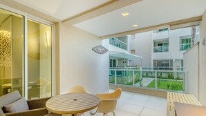 A modern apartment with a balcony, a dining area with a round table and chairs, and a view of the building's exterior.