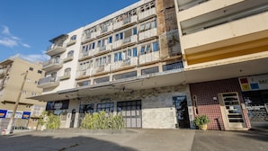Un edificio de varios pisos con balcones, una tienda y un área de estacionamiento.