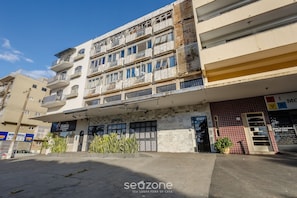 Un edificio de varios pisos con balcones, una tienda y un área de estacionamiento.
