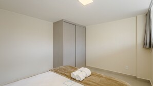 Un dormitorio minimalista con una cama, un armario y una lámpara en el techo.