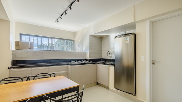 Una cocina moderna con refrigerador de acero inoxidable, ventana sobre el fregadero y comedor con mesa y sillas.