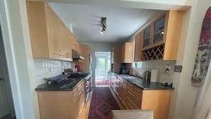 A kitchen with wooden cabinets, a black countertop, and a red patterned rug.