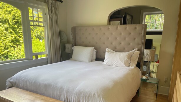 A neatly made bed with a headboard, a bedside table, and a bench.
