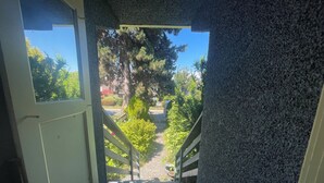 A staircase leading to a covered outdoor area with a view of trees and a pathway.