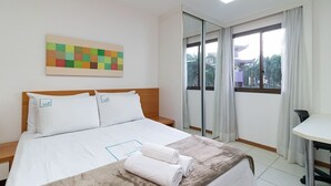 Une chambre d’hôtel avec un lit, un bureau et une grande fenêtre avec des rideaux.