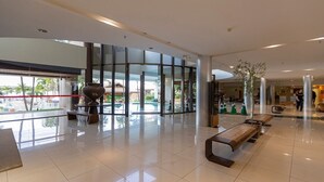 Un hall d’entrée spacieux avec une grande porte vitrée donnant sur l’extérieur, un espace salon central et un grand vase décoratif.