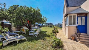 A sunny outdoor area with lounge chairs and a tree, a building with a blue door, and a clear sky. - Lovely home in Plouhinec with WiFi (Plouhinec)