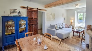 A cozy living room with a wooden dining table, a blue cabinet with glass doors, a grey sofa, and a fireplace. - Lovely home in Plouhinec with WiFi (Plouhinec)